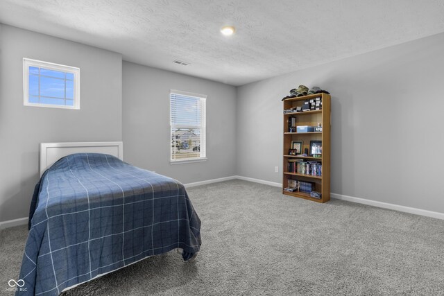 carpeted bedroom with visible vents, baseboards, and a textured ceiling