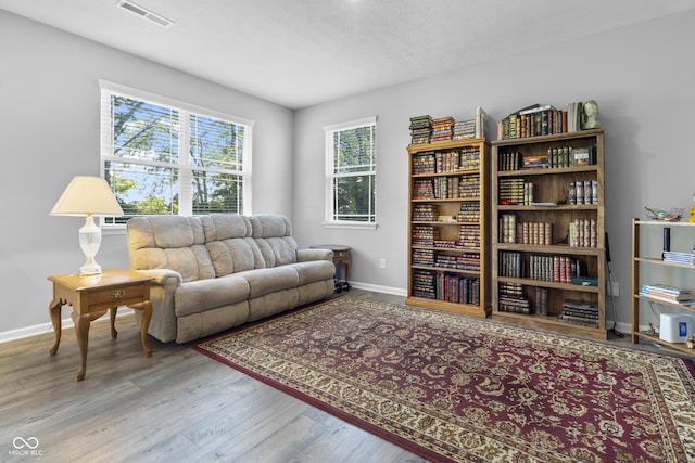 living area with visible vents, light wood-style flooring, baseboards, and a textured ceiling