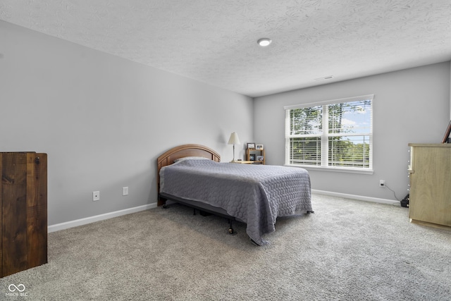 carpeted bedroom featuring a textured ceiling and baseboards