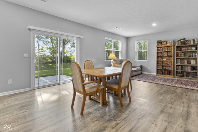 dining room with light wood-type flooring, baseboards, and a textured ceiling