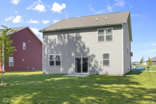 back of house featuring a shingled roof and a lawn