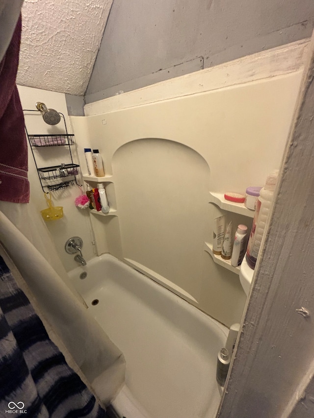 bathroom featuring lofted ceiling and tub / shower combination