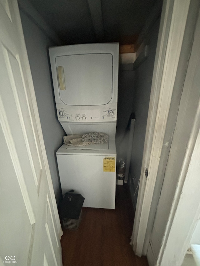 clothes washing area featuring dark wood-type flooring and stacked washer and clothes dryer