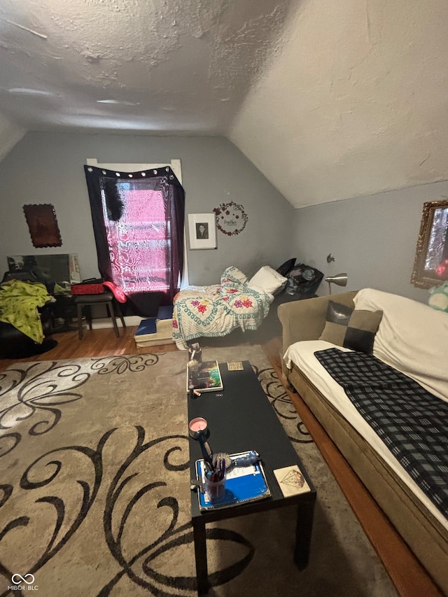 bedroom featuring a textured ceiling, vaulted ceiling, and hardwood / wood-style flooring