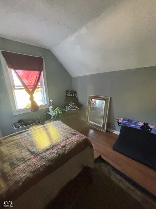 bedroom with hardwood / wood-style flooring, lofted ceiling, and a textured ceiling