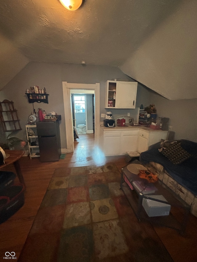 interior space with dark hardwood / wood-style floors, lofted ceiling, and a textured ceiling