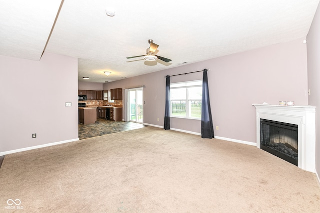 unfurnished living room featuring ceiling fan and carpet floors