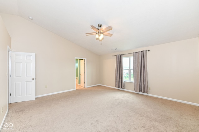 spare room featuring ceiling fan, light carpet, and vaulted ceiling