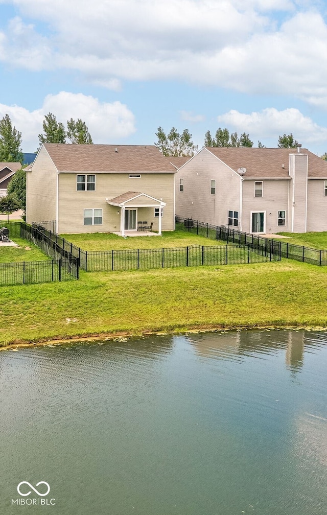 back of property with a water view and a lawn