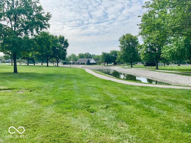 surrounding community with a water view and a lawn