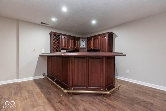 bar with dark brown cabinets and wood-type flooring