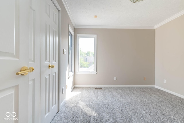 carpeted empty room featuring a textured ceiling and crown molding