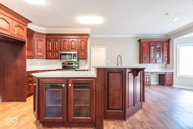 kitchen featuring appliances with stainless steel finishes, a textured ceiling, and a center island with sink