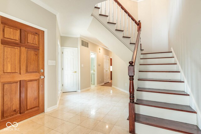 foyer with ornamental molding and light tile patterned floors