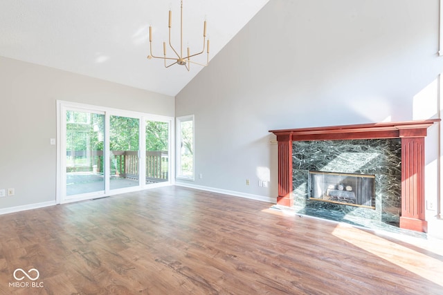 unfurnished living room featuring an inviting chandelier, high vaulted ceiling, a fireplace, and hardwood / wood-style flooring