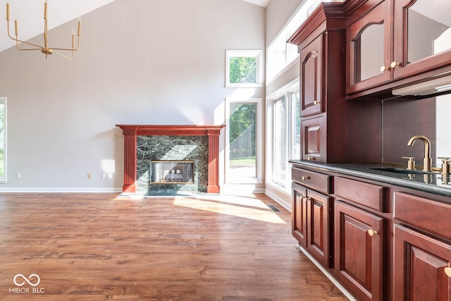 unfurnished living room with sink, a fireplace, high vaulted ceiling, and hardwood / wood-style floors