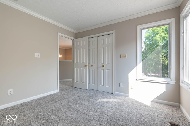 unfurnished bedroom featuring a textured ceiling, ornamental molding, a closet, and carpet flooring