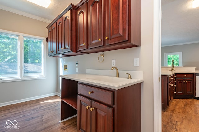 kitchen with hardwood / wood-style floors, stainless steel dishwasher, ornamental molding, and sink