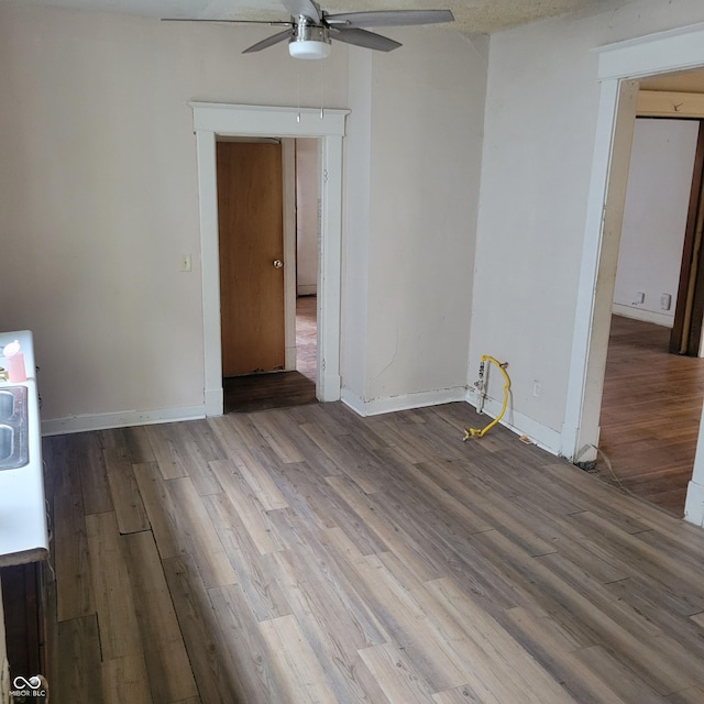 empty room featuring a ceiling fan, baseboards, and light wood finished floors