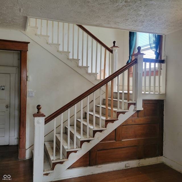 stairway featuring a textured ceiling and wood finished floors