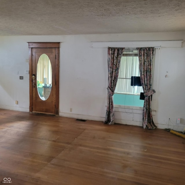 foyer featuring visible vents, a textured ceiling, and wood finished floors