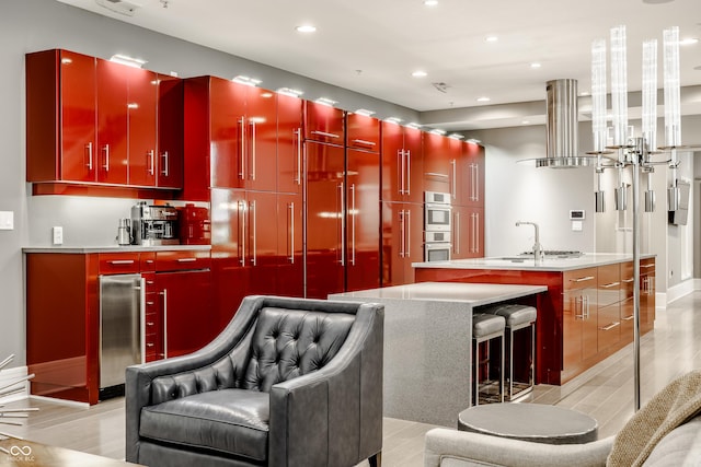 bar with paneled built in fridge, sink, double oven, light hardwood / wood-style floors, and extractor fan