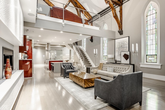 living room with a wealth of natural light, light hardwood / wood-style flooring, and a high ceiling