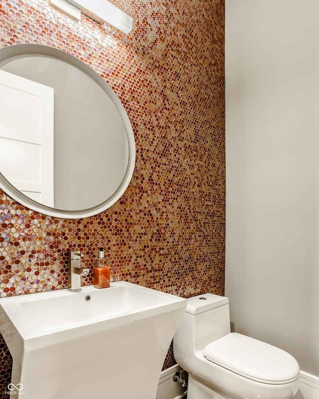 bathroom with backsplash, toilet, and sink