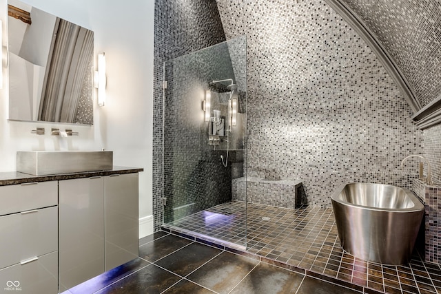 bathroom featuring plus walk in shower, vanity, tile patterned floors, and tile walls