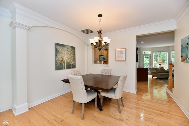 dining space with decorative columns, wood-type flooring, crown molding, and an inviting chandelier