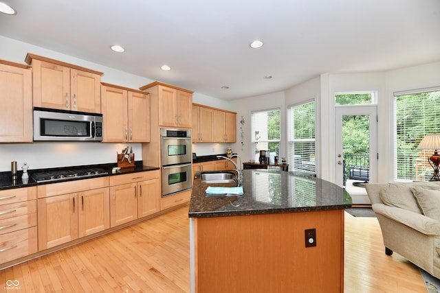 kitchen featuring a center island with sink, sink, light hardwood / wood-style flooring, appliances with stainless steel finishes, and light brown cabinetry