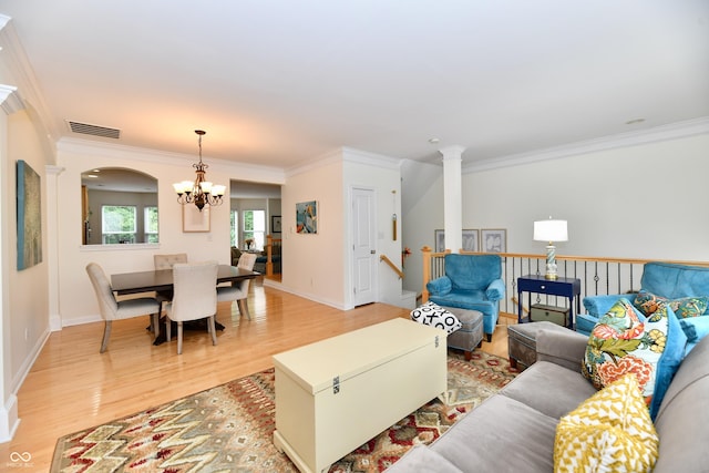 living room featuring hardwood / wood-style flooring, decorative columns, ornamental molding, and a chandelier