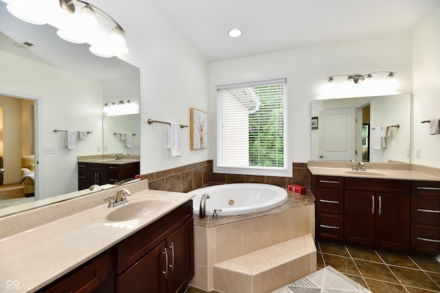 bathroom featuring tiled tub, vanity, and tile patterned flooring