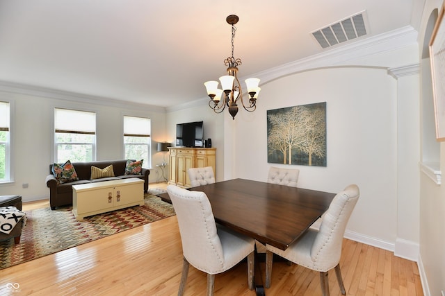 dining area featuring a chandelier, light wood-type flooring, and ornamental molding