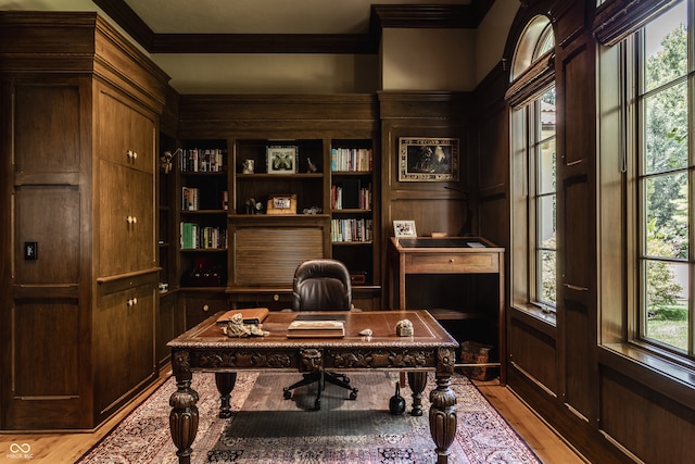 home office with light wood-type flooring, wooden walls, and crown molding