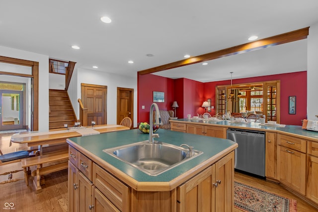 kitchen featuring a kitchen island with sink, sink, light hardwood / wood-style flooring, stainless steel dishwasher, and beam ceiling