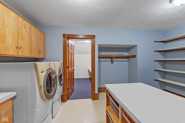 laundry area with washer and clothes dryer, cabinets, and a textured ceiling