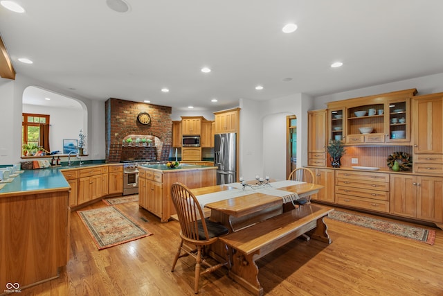 kitchen featuring kitchen peninsula, appliances with stainless steel finishes, light wood-type flooring, tasteful backsplash, and sink