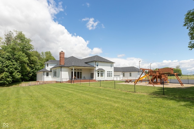 back of house with a lawn and a playground