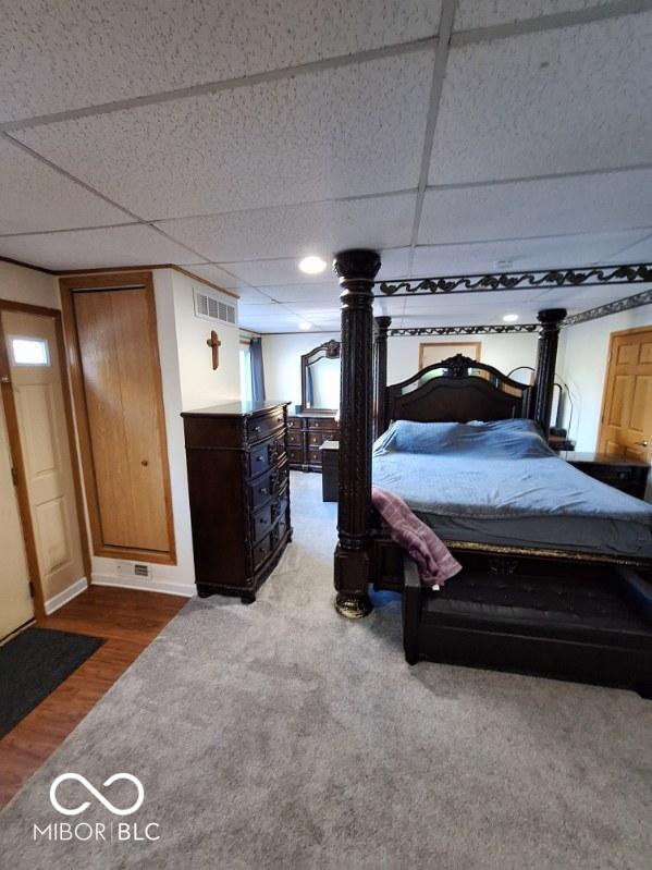 unfurnished bedroom with visible vents, a drop ceiling, and wood finished floors