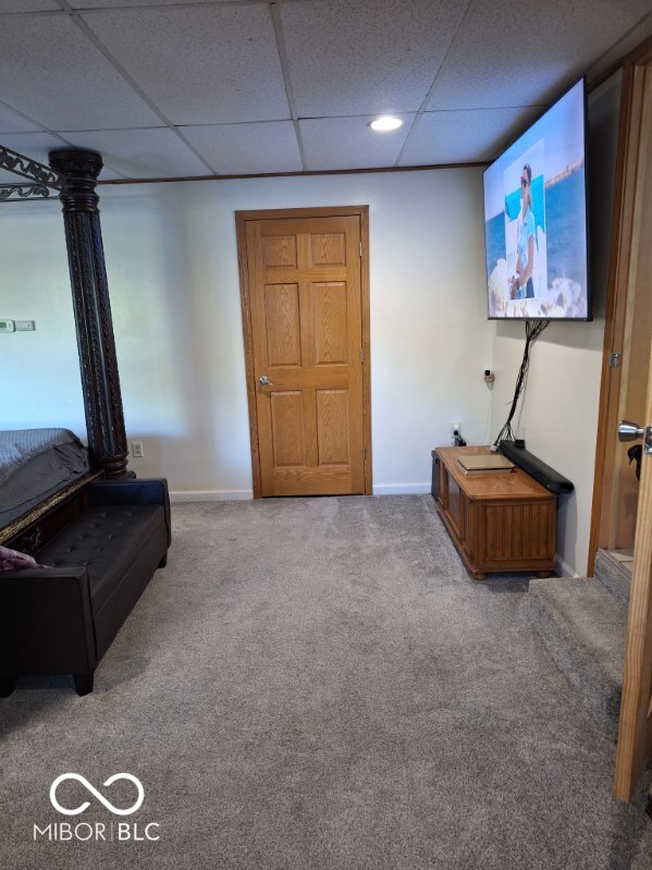 unfurnished living room with a paneled ceiling, baseboards, and carpet flooring