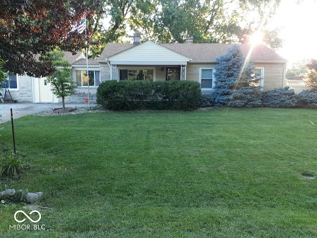 view of front facade featuring driveway, a chimney, and a front yard