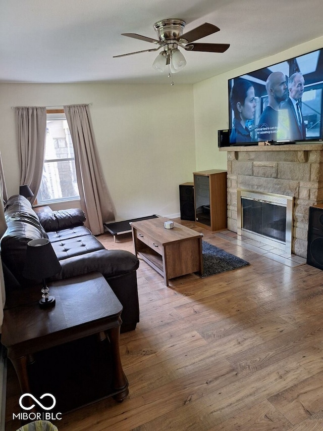 living room featuring a ceiling fan, a fireplace, and wood finished floors