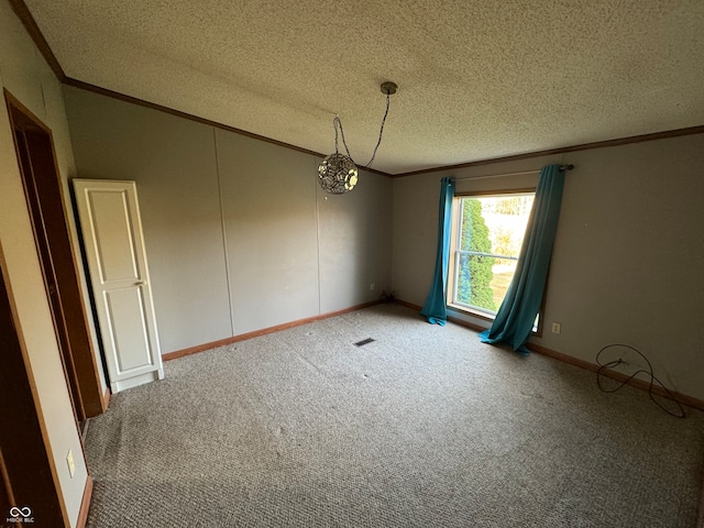 carpeted empty room with ornamental molding and a textured ceiling