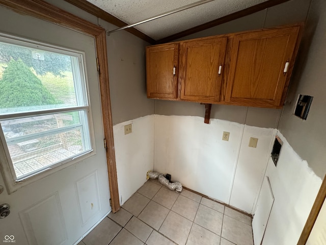 laundry room with cabinets, light tile patterned floors, a textured ceiling, and a wealth of natural light