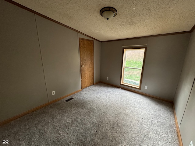 empty room featuring lofted ceiling, light colored carpet, ornamental molding, and a textured ceiling