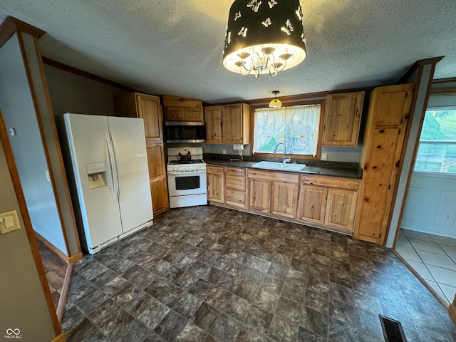 kitchen featuring sink, white appliances, a textured ceiling, and a healthy amount of sunlight