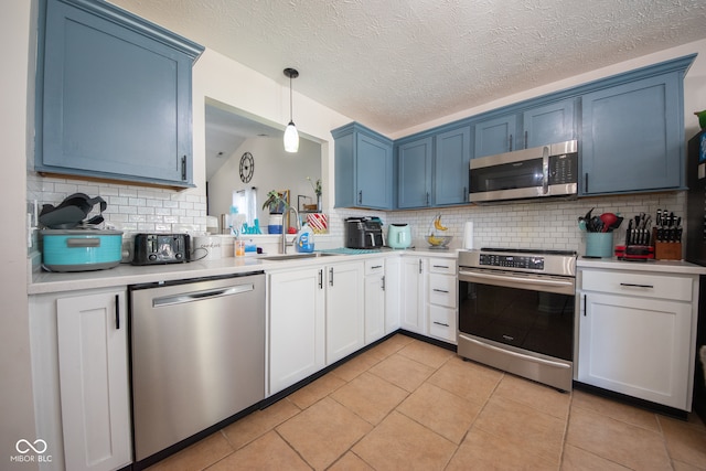 kitchen with hanging light fixtures, light tile patterned floors, appliances with stainless steel finishes, backsplash, and blue cabinets