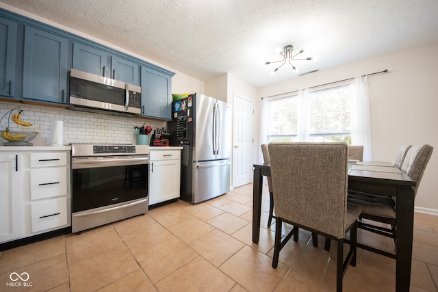 kitchen with white cabinetry, blue cabinetry, appliances with stainless steel finishes, and light tile patterned floors