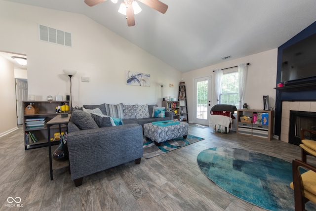 living room featuring hardwood / wood-style floors, a tiled fireplace, high vaulted ceiling, and ceiling fan